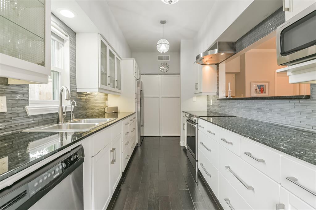 Glass cabinetry, sleek glass backsplash, granite counters and modern hardware highlight this stunning kitchen.  Storage abounds with the large pantry at the end of the kitchen.