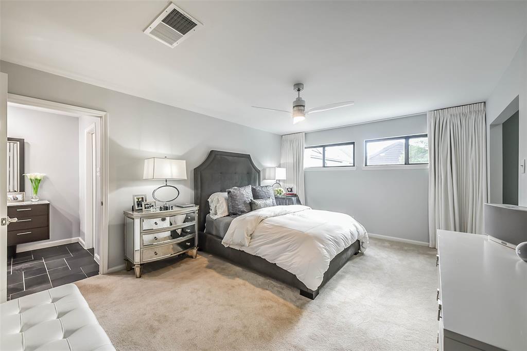 Relax in the serene primary retreat boasting a lucite ceiling fan and ample room for a seating area.