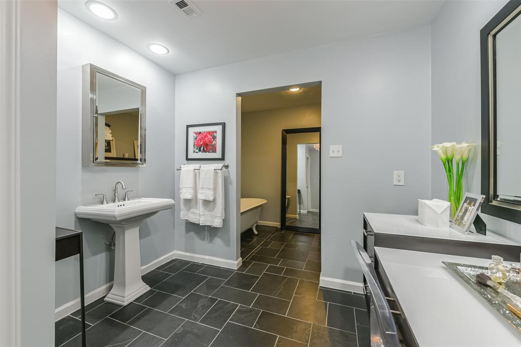 Primary bath provides a haven to unwind with a clawfoot soaking tub and a glass topped built in vanity.