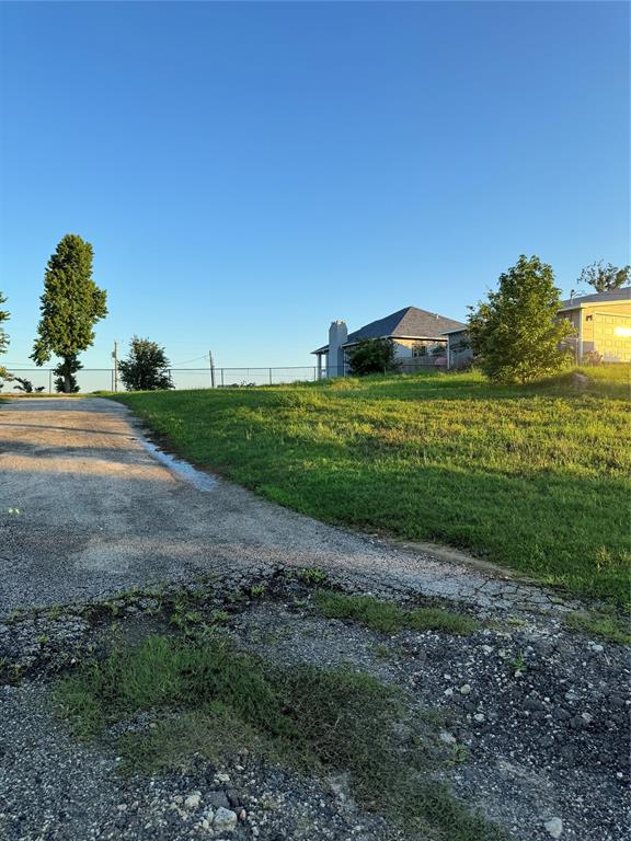 Driveway leads up to garage salb and flat ground to build your home.