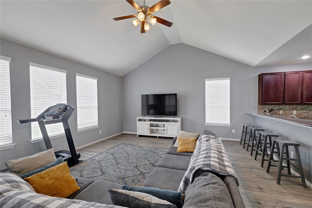 Living room with vaulted ceiling, ceiling fan and faux wood-tile flooring.