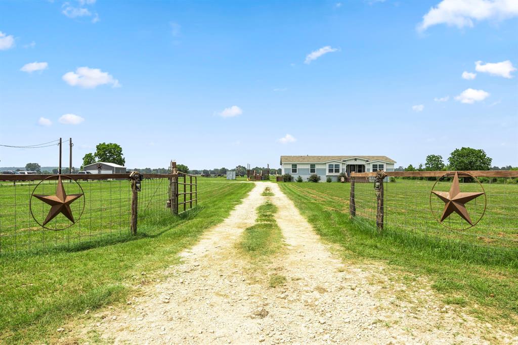 Gravel driveway leads you to the left side of the home where you can see the elevated patio and firepit