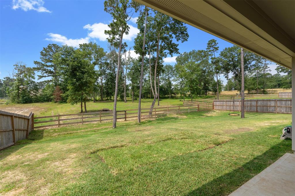 Covered back patio overlooking the fenced back yard. Property continues past the fence for even more space and so many options!