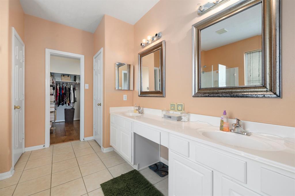 This primary bathroom is definitely move-in ready! Featuring white cabinets with light countertops, spacious walk-in closet with shelving, unique mirrors, custom paint, a spot for a vanity seat and sleek finishes.