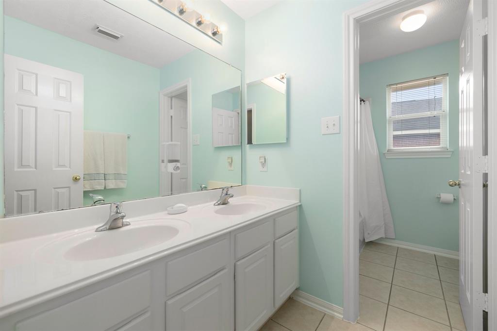 Secondary bathroom features light countertops and cabinets, custom paint, shower/tub combo with tile surround, large mirror, tile floors, sleek fixtures and plenty of space to accommodate any visiting family or guests.