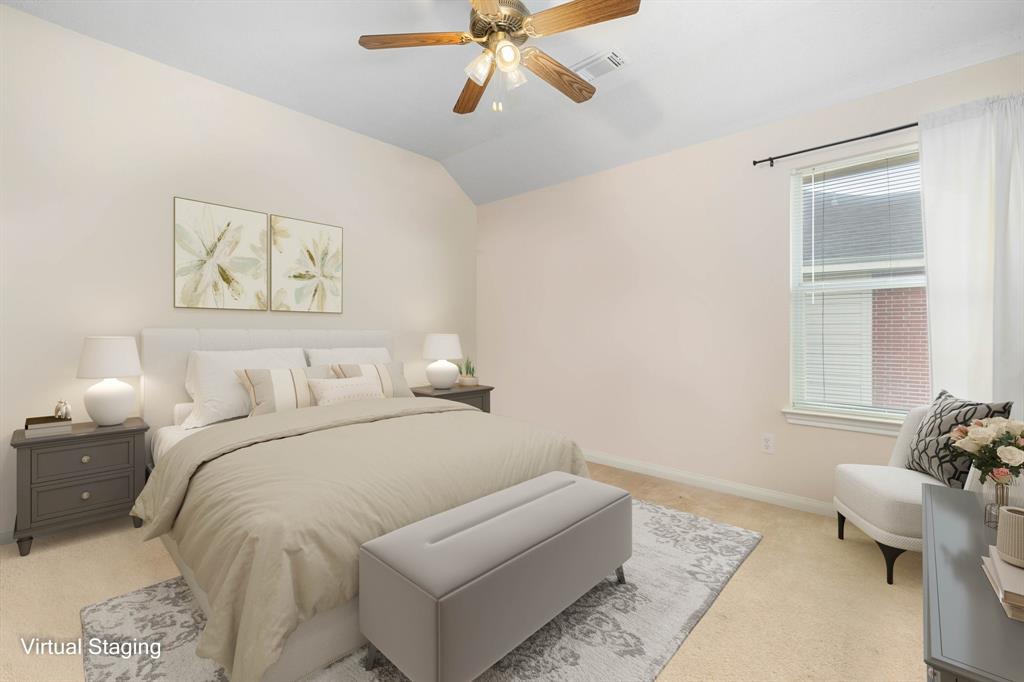 Secondary bedroom features plush carpet, custom paint, dark stained ceiling fan with lighting and a large window with privacy blinds.