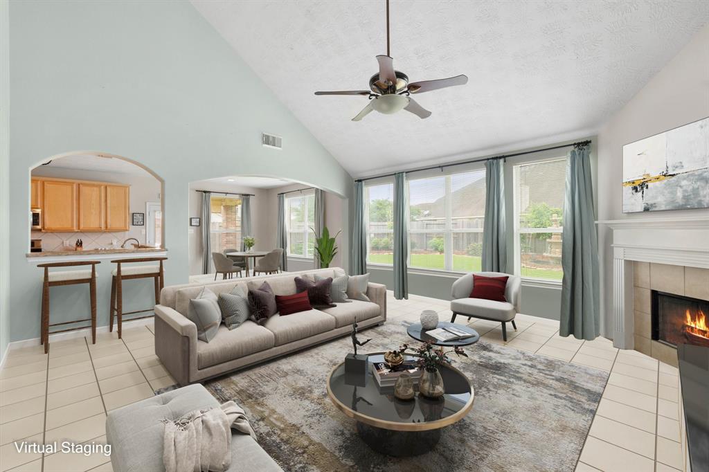 Gather the family and guests together in your lovely living room! Featuring soaring high ceilings, dark stained ceiling fan, custom paint, gorgeous tile floors and large windows that provide plenty of natural lighting throughout the day.