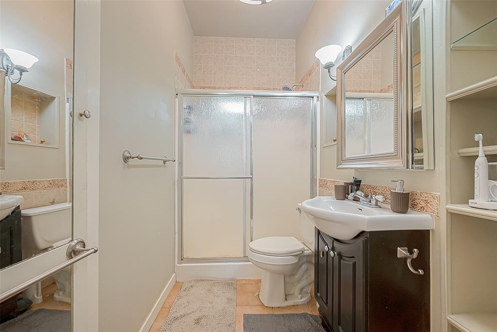 Bathroom feature walk-in shower, single vanity, storage mirror, and built-ins.