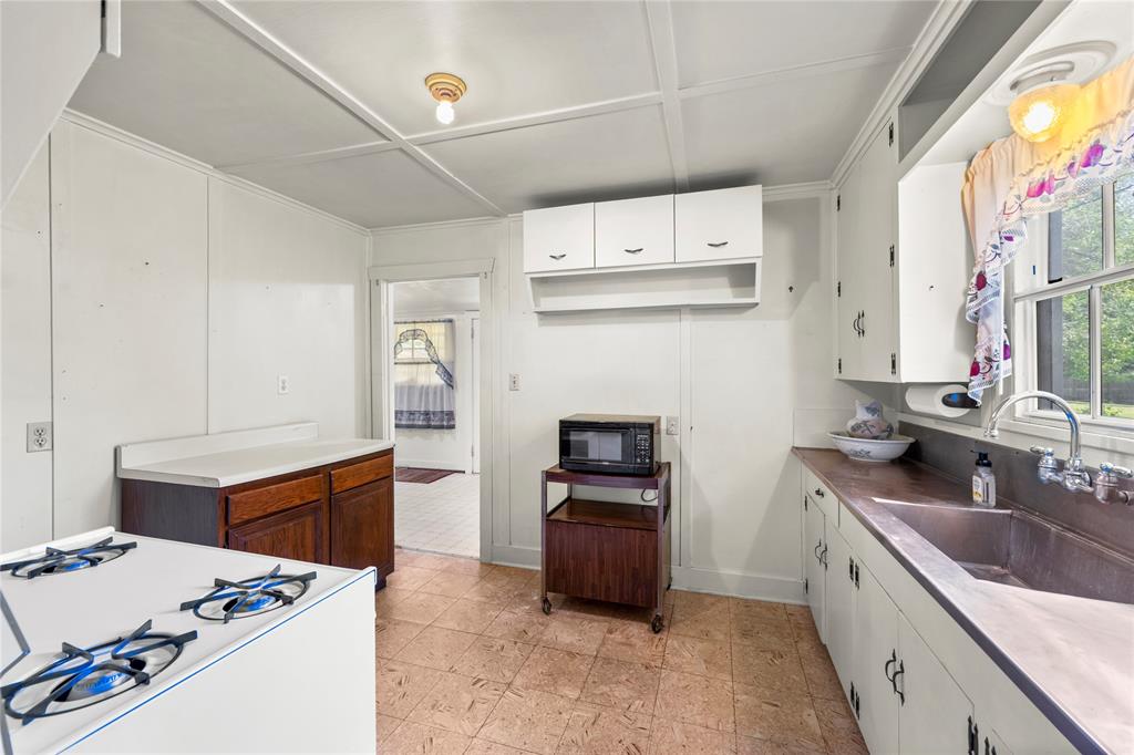 Kitchen view with gas range.  Kitchen counter and sink is a single unit made from stainless steel. Window over the sink faces east.