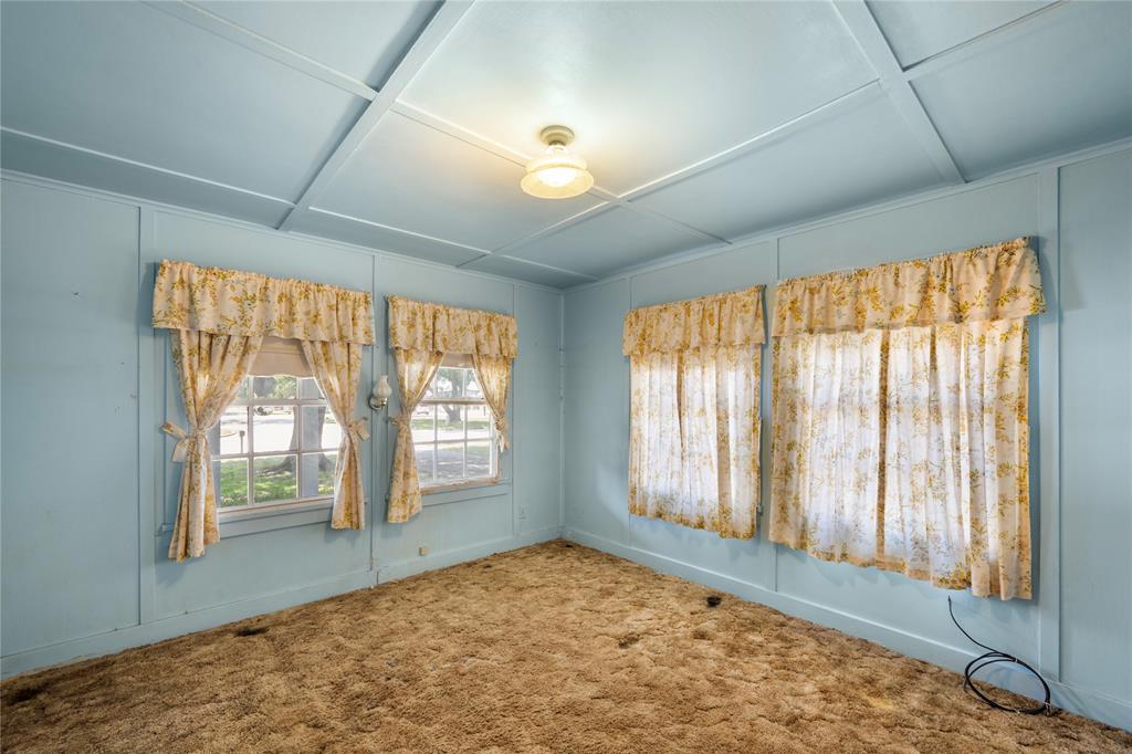 Front bedroom of home has windows on two sides facing front of home and driveway. Walls and ceiling are all original to home.