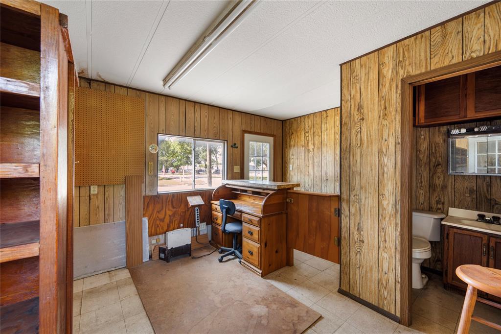 Inside the locksmith building is a half bath, shelving, a desk and lighting. Window unit provides AC.