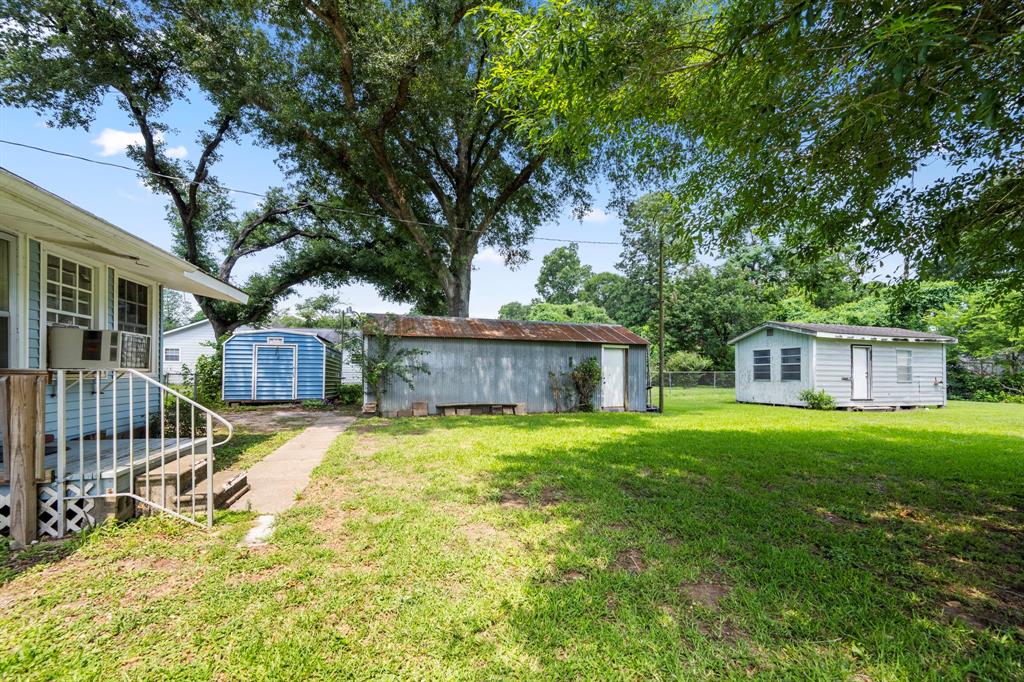 Back view of home, metal storage building, corrugated tin garage and additional small house.