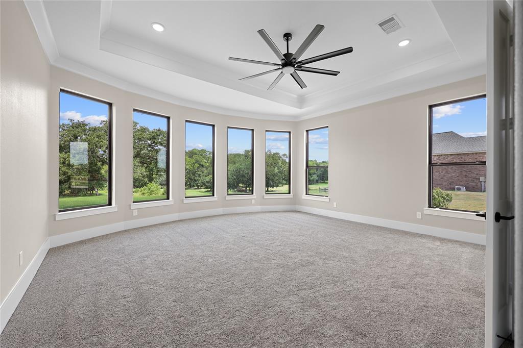 On the other side of the home, this is your stately primary bedroom with incredible views of nature as you wake up each morning. Tray accent ceilings in this room will be home to a large fan for maximum comfort.