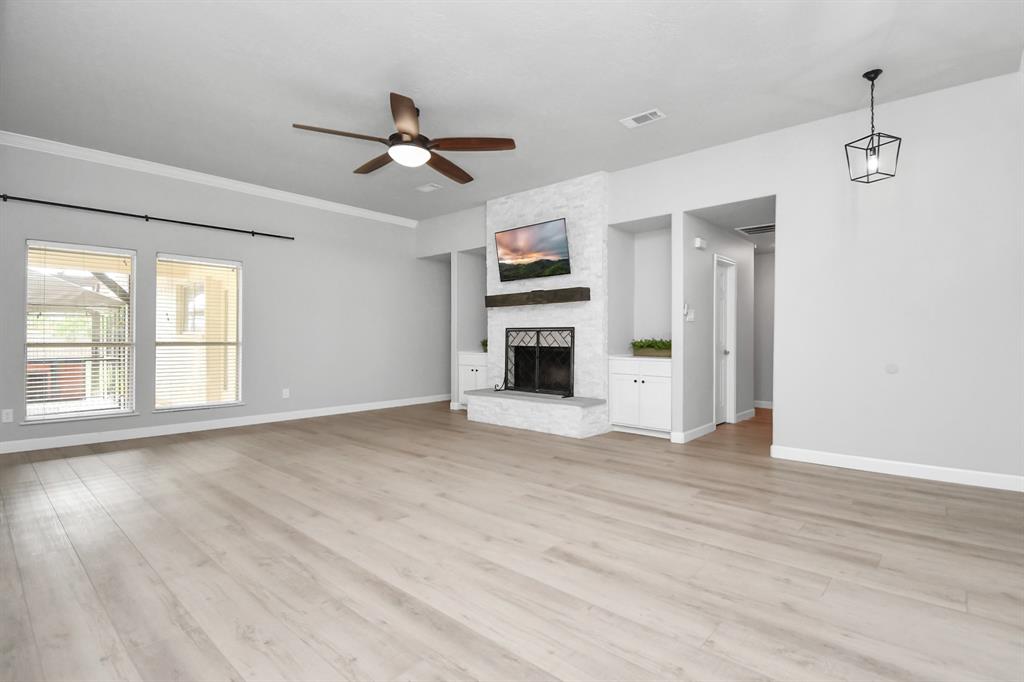 Large family room with custom cabinetry and stone-accented fireplace