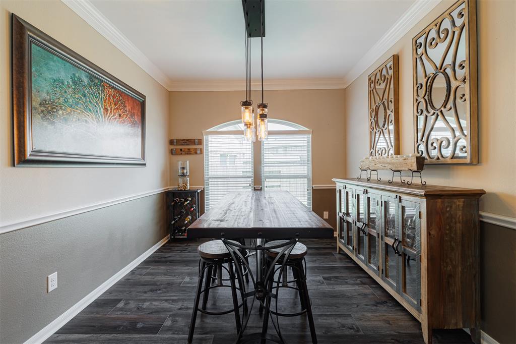 The formal dining room features crown and chair rail molding, luxury vinyl plank flooring and a pendant style chandelier.