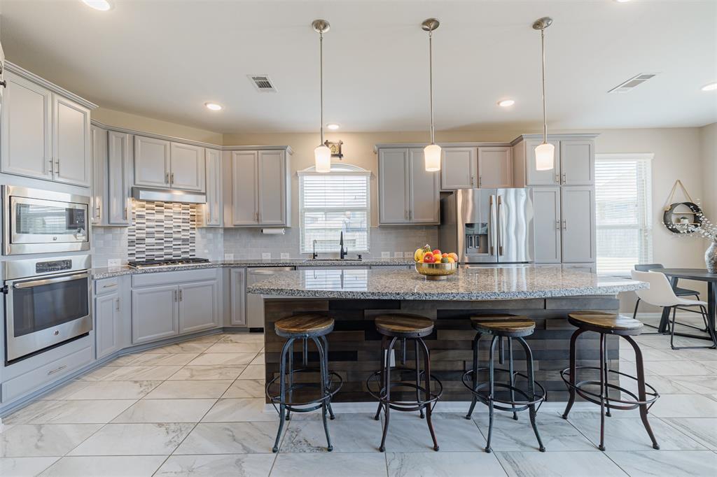 The gourmet island kitchen has granite counters, tile backsplash, pendant lighting, and stainless steel appliances.