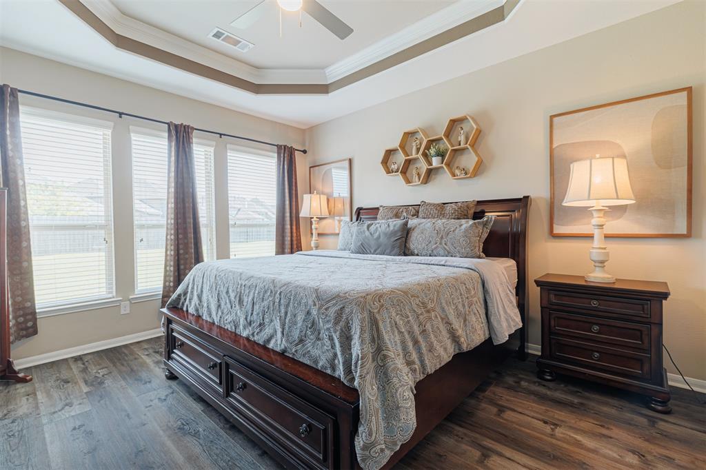 Luxurious primary suite with tray ceiling, crown molding and luxury vinyl plank flooring.