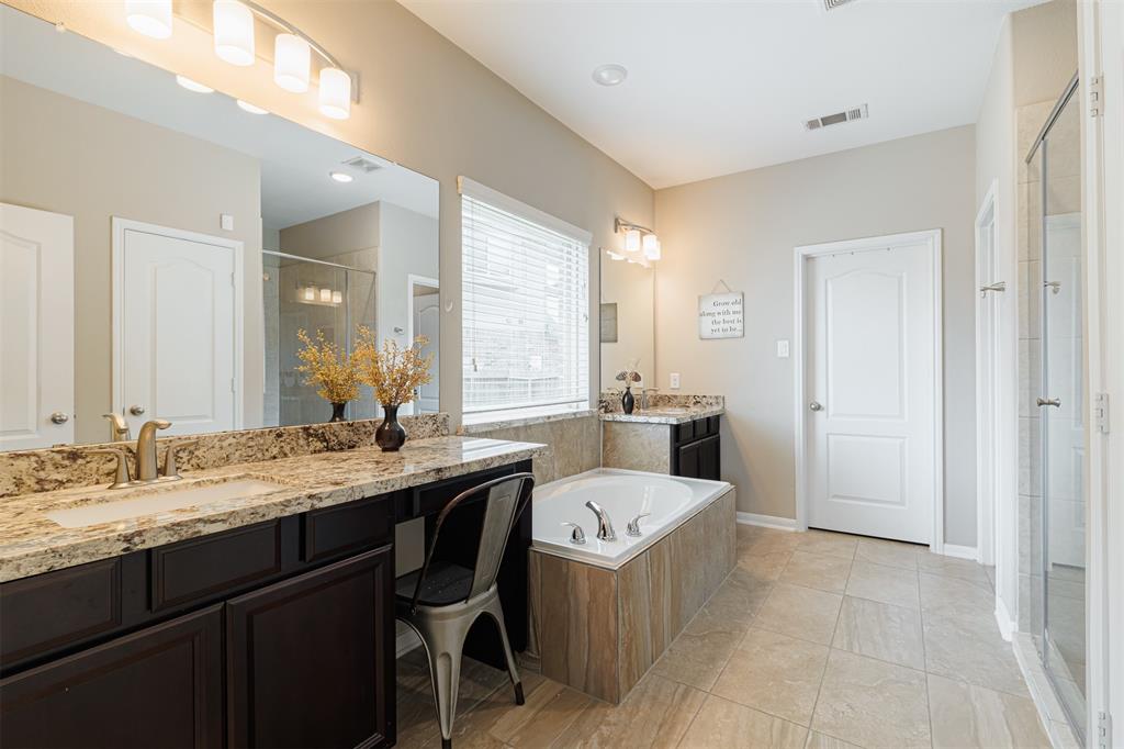 Luxurious primary bath with granite counters and tile flooring.