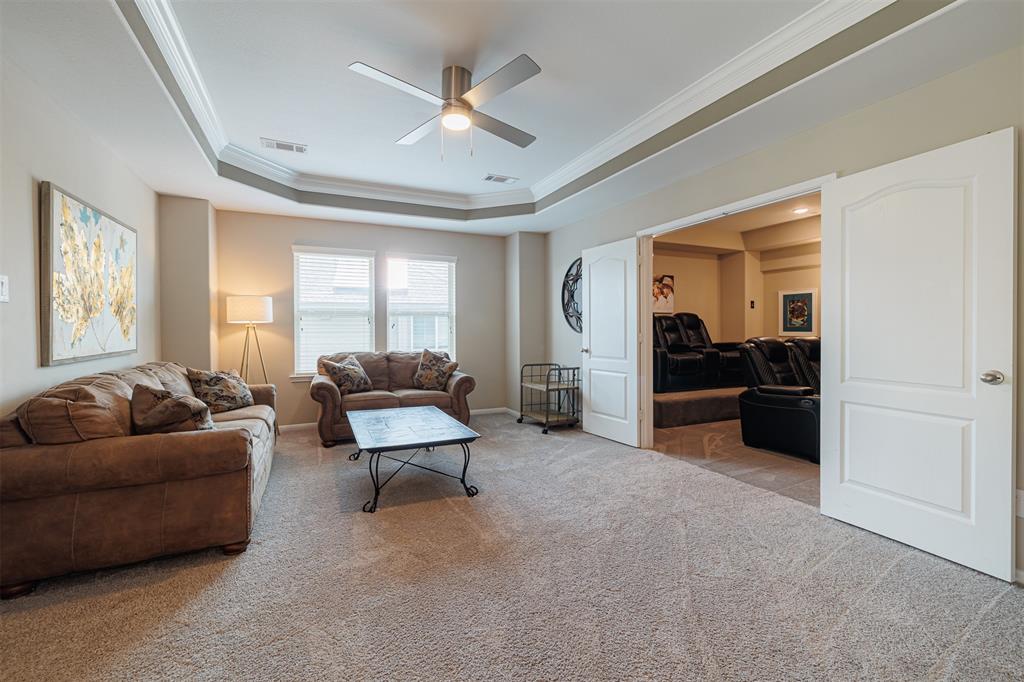 Spacious game room upstairs featuring a tray ceiling with crown molding.