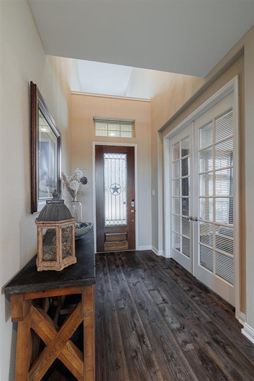 Foyer with luxury vinyl plank flooring and high ceilings leads to the study with double French doors.