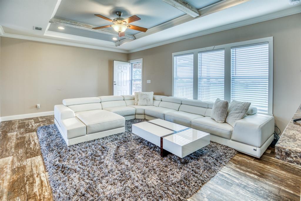 The living area exudes warmth and comfort, with a plush sectional sofa and a rustic wood accent wall that complements the modern amenities.