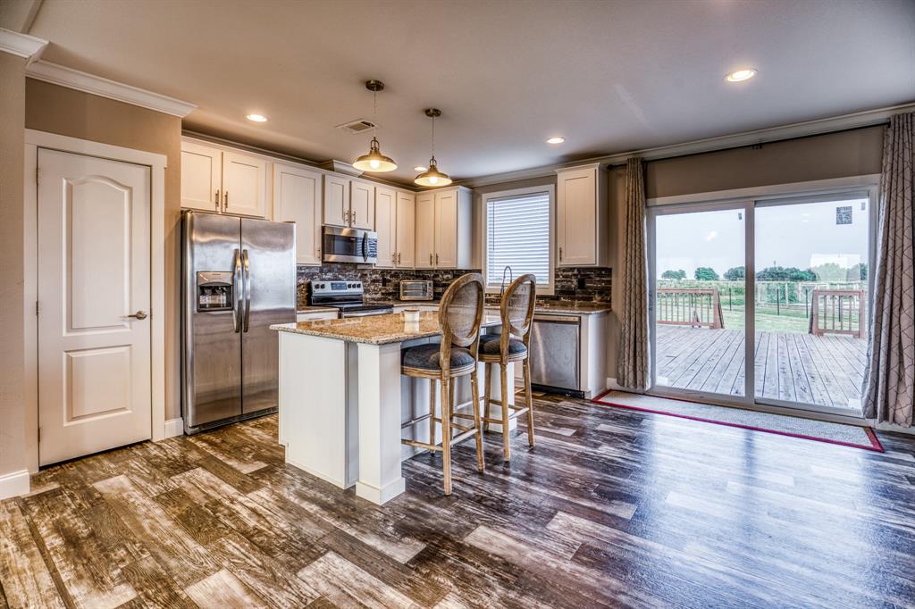 The kitchen is a chef’s dream, featuring gleaming stainless steel appliances, granite countertops, and pristine white cabinetry.