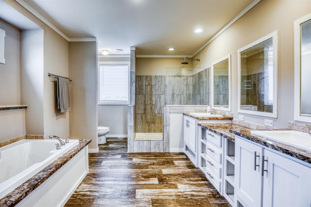 A tranquil en-suite bathroom featuring a soaking tub, walk-in shower, and dual vanities.