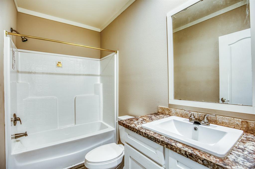 The vanity area is both stylish and functional, featuring a polished granite countertop that complements the rich wooden flooring. The pristine white sink is set into the countertop, providing a seamless look that enhances the bathroom\'s modern aesthetic.