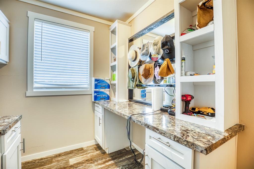 Adjoining the mud room is the well-appointed laundry room, designed to make household chores more convenient and efficient. The same granite countertop extends into this space, offering a generous area for folding clothes and other tasks. White cabinetry provides ample storage for laundry supplies, keeping the room neat and tidy.