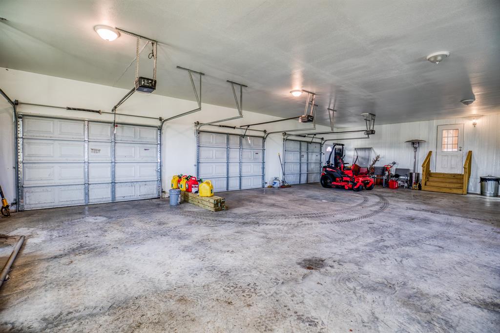 Equipped with three automatic garage doors, each providing easy access to separate bays, this garage is perfect for storing cars, tractors, lawn equipment, and more. The sturdy construction and clean, white walls create a professional and organized environment, ideal for any hobbyist or professional mechanic. With direct access to the home, transitioning between indoor and outdoor tasks is seamless and convenient.