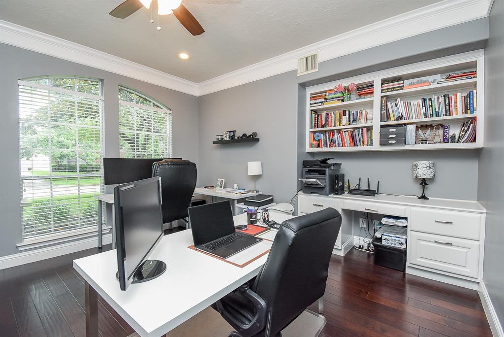 Cool walls are beautifully complemented by rich wood flooring; with a lovely double arched window bathing this special space in natural light. Enjoy the marvelous built-in shelving and desk space.