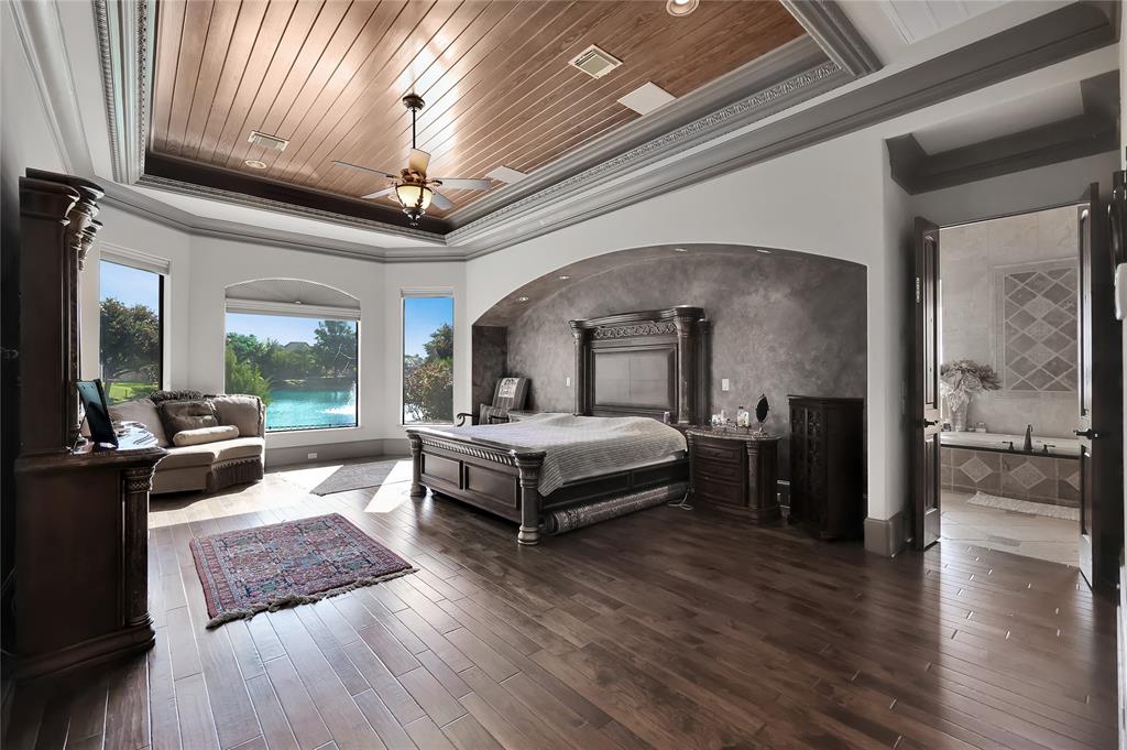 Primary Suite Oasis with wonderful wood flooring, coffered ceiling with wood paneling and crown moldings, arched niche, sitting area with top Duette Ultra Glide honeycomb shades to retreat