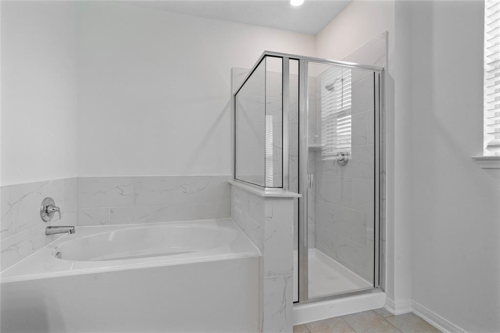 This primary bathroom is definitely move-in ready! Featuring a framed oversized walk-in shower with tile surround, stained cabinets with light countertops, spacious walk-in closet with shelving, high ceilings, custom paint, sleek and modern finishes.