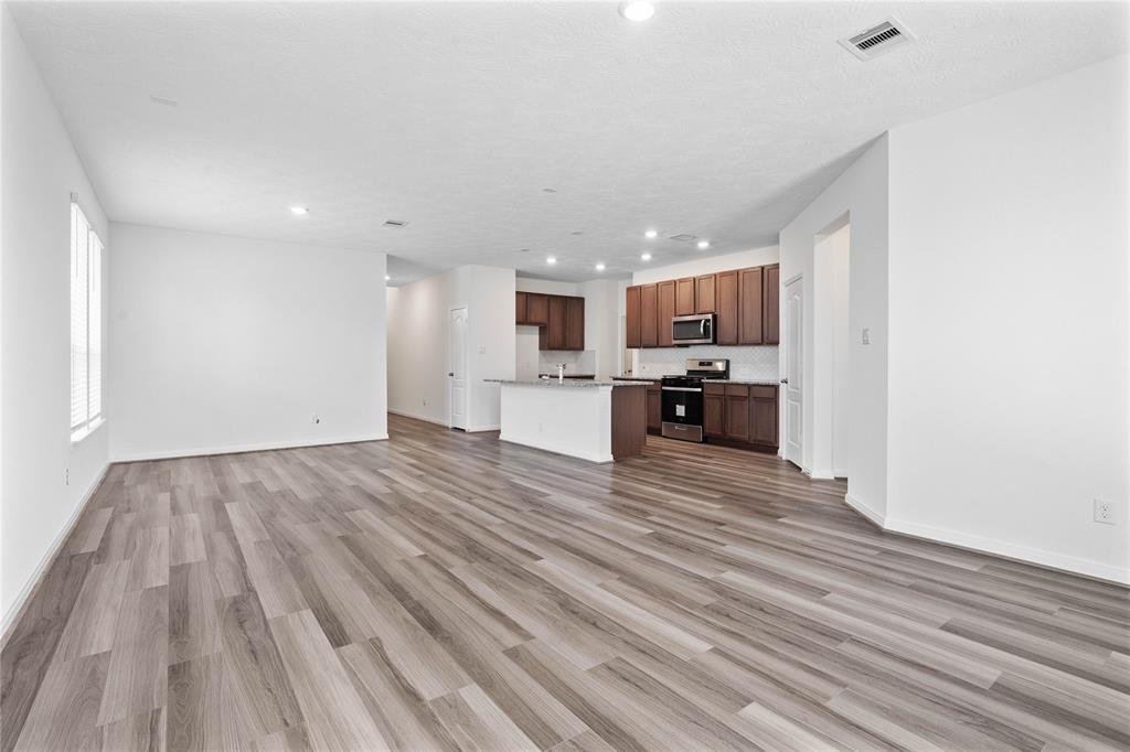 Another view of the Great Room featuring the beautiful vinyl plank flooring, looking into the Kitchen and Dining.