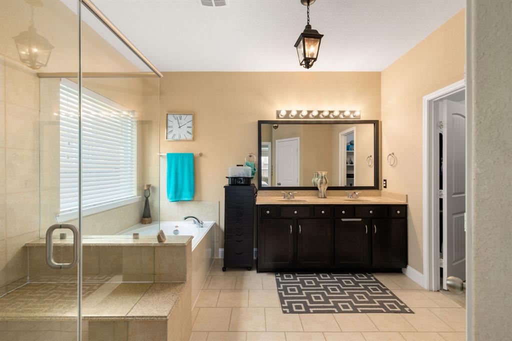 This primary bathroom is definitely move-in ready! Featuring a steel framed walk-in shower with tile surround, separate garden tub for soaking after a long day with custom tile detailing, dark stained cabinets with light countertops, spacious walk-in closet with shelving, custom paint, sleek and dark modern finishes.