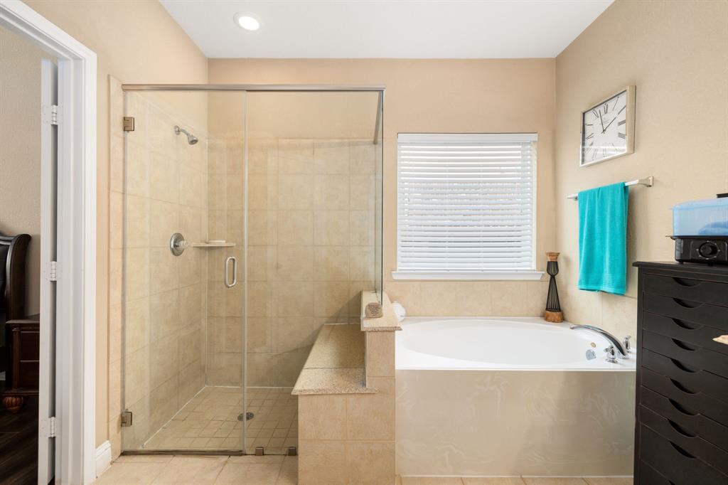 This additional view of the primary bath showcases a walk-in shower with tile surround and a separate garden tub perfect for soaking after a long day.