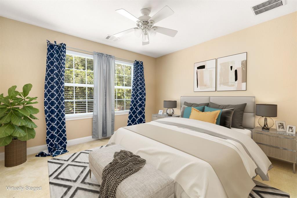 Secondary bedroom features plush carpet, custom paint, ceiling fan with lighting and a large window with privacy blinds.