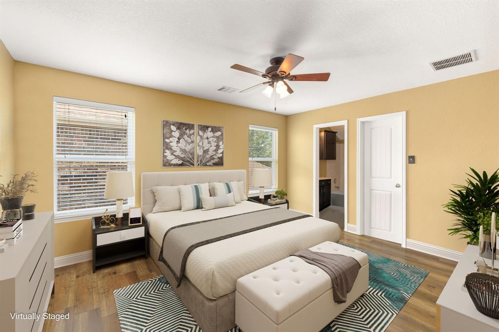 Secondary bedroom features wood flooring, custom paint, dark stained ceiling fan with lighting and a large window with privacy blinds.