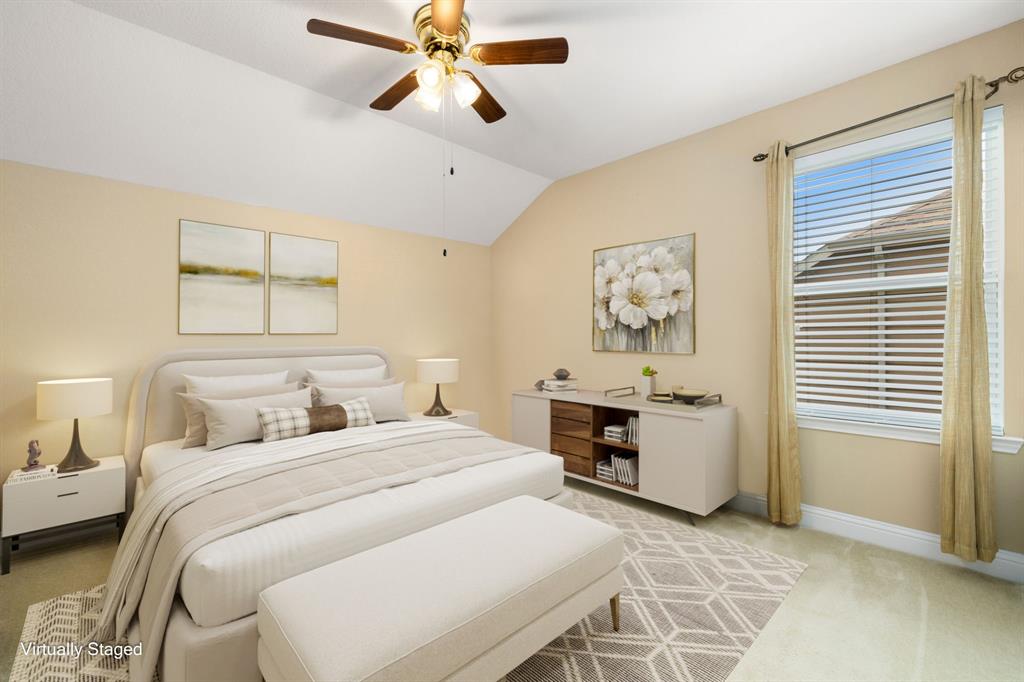 Secondary bedroom features plush carpet, custom paint, dark stained ceiling fan with lighting and a large window with privacy blinds.