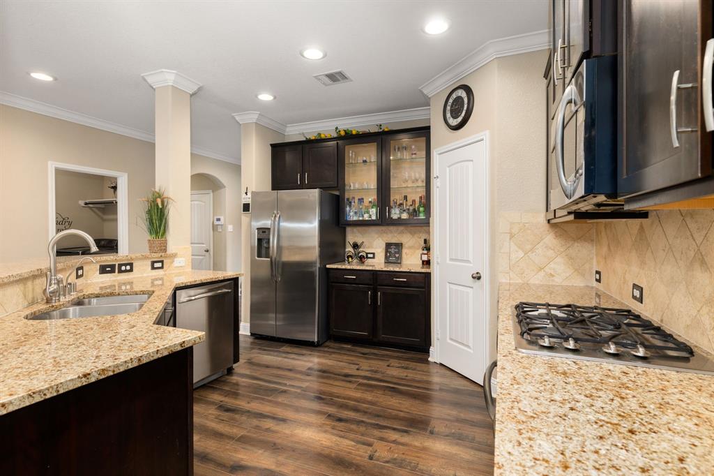 This additional view of your gorgeous kitchen showcases the wood floors, SS appliances apart of the kitchen, granite countertops, and recessed lighting.