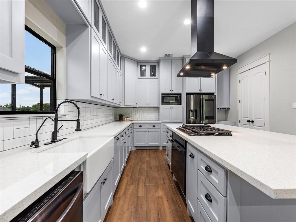 Kitchen features: Quartz counter tops, subway backsplash, black hardware, farm house sink, tons of cabinetry, dry bar with a wine rack, gas cook top, and this large island!