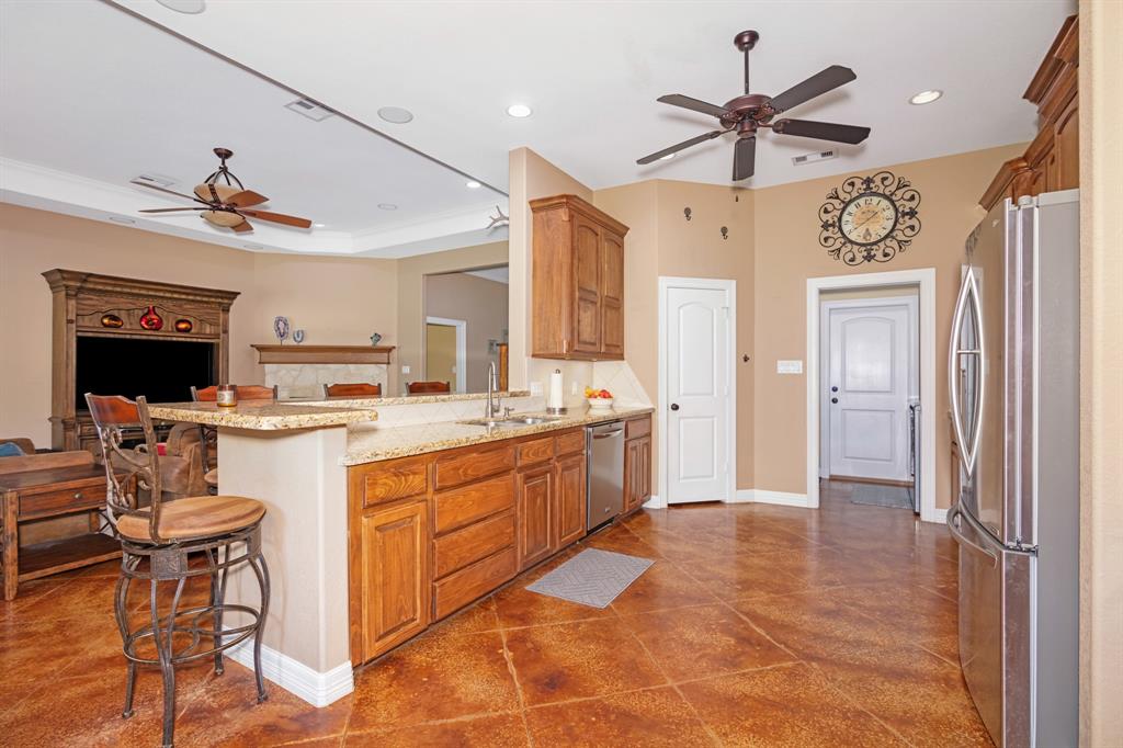 Spacious kitchen with bar seating, wooden cabinets, stainless steel appliances, and a view of the dining area and living room.