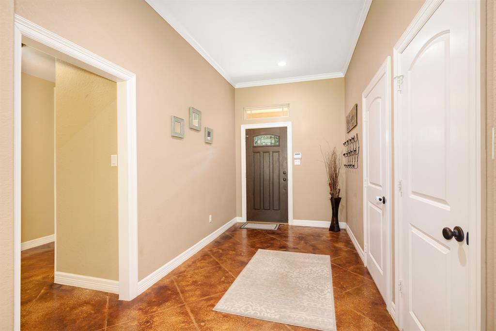 Warm-toned residential entryway with a front door, decorated walls, and a marbled floor.