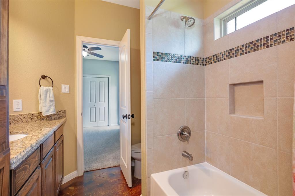 Spacious hollywoodl bathroom with a tiled shower, bathtub, and granite countertop,