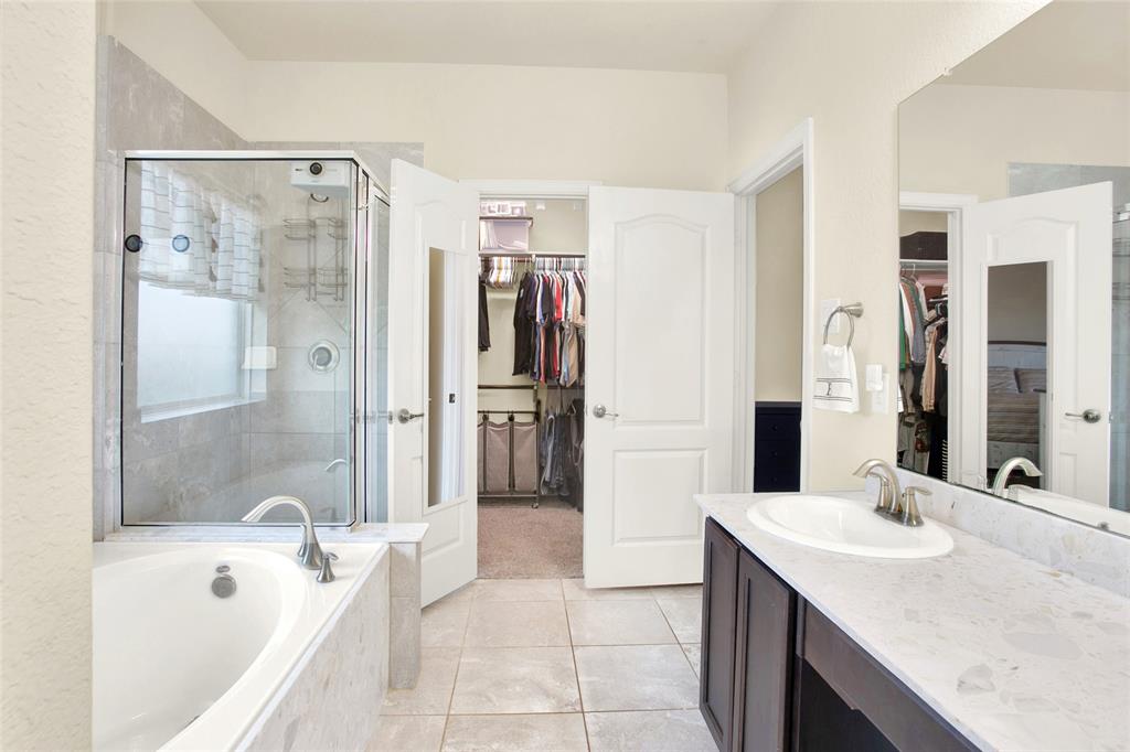 Owners ensuite bathroom with quartz countertops, round china bowls, maple cabinets, shower with glass door and a large garden tub with tile accents.