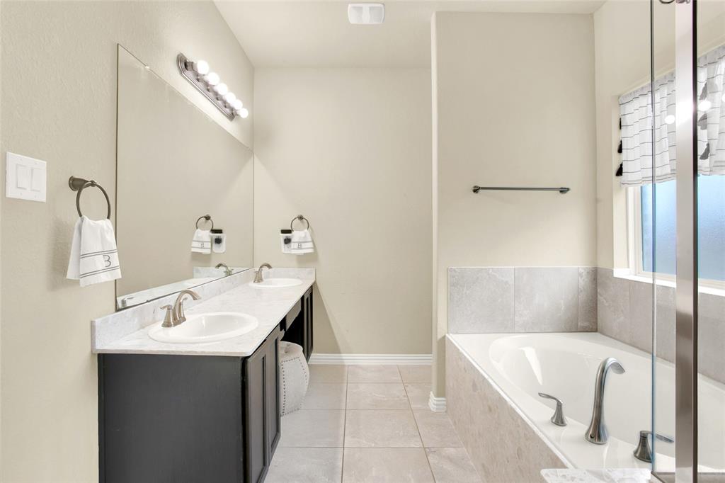 Owners ensuite bathroom with quartz countertops, round china bowls, maple cabinets, shower with glass door and a large garden tub with tile accents. Elongated commode well hidden behind the wall for privacy.