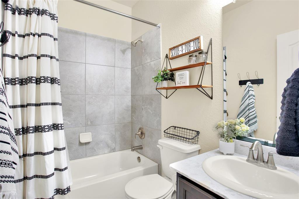 Secondary bathroom with beautiful tile walls, maple cabinets, and a large mirror.