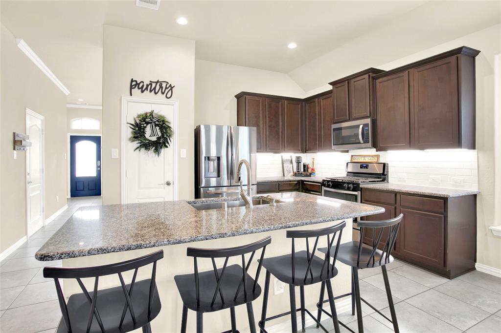 A nicely appointed chef style kitchen with maple cabinets, crown molding, under cabinet lighting, tile backsplash and Moen Fixtures.