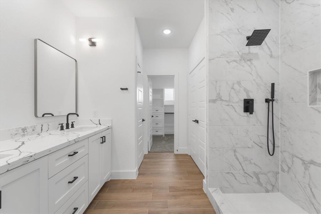 Large walk in shower with a soap niche and handheld showerhead extension.