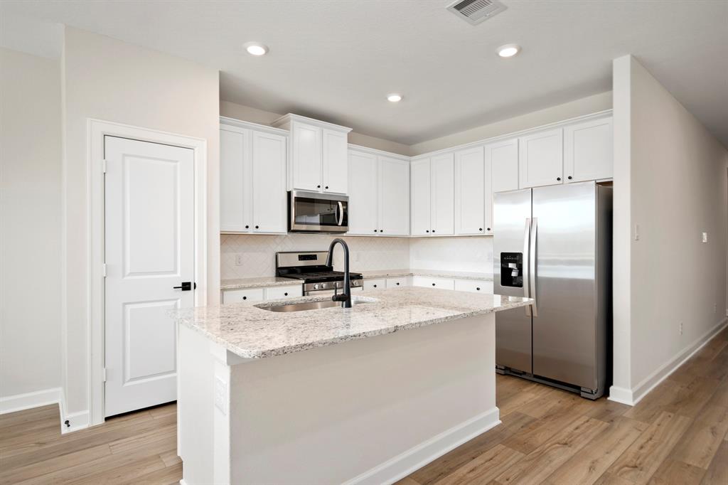 The kitchen boast sleek white countertops that gleam under the soft glow of led lights, accentuating the modern elegance of the space.